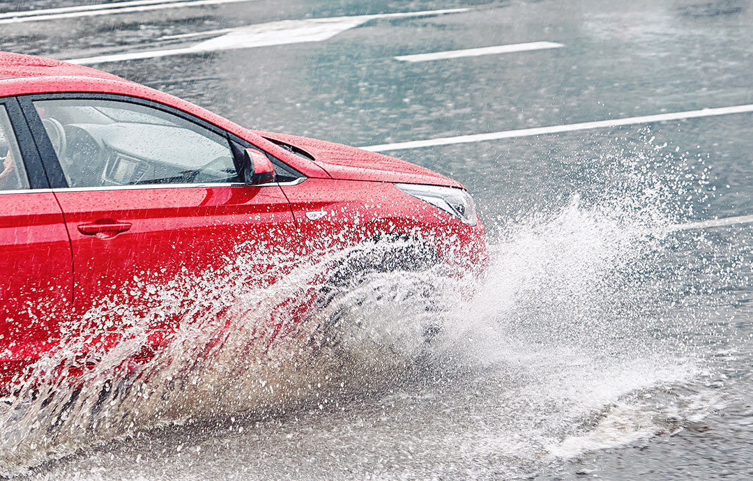 雨の中走る赤い車