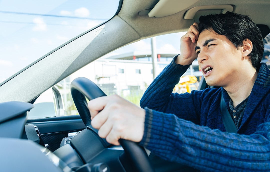 運転席で悩む男性